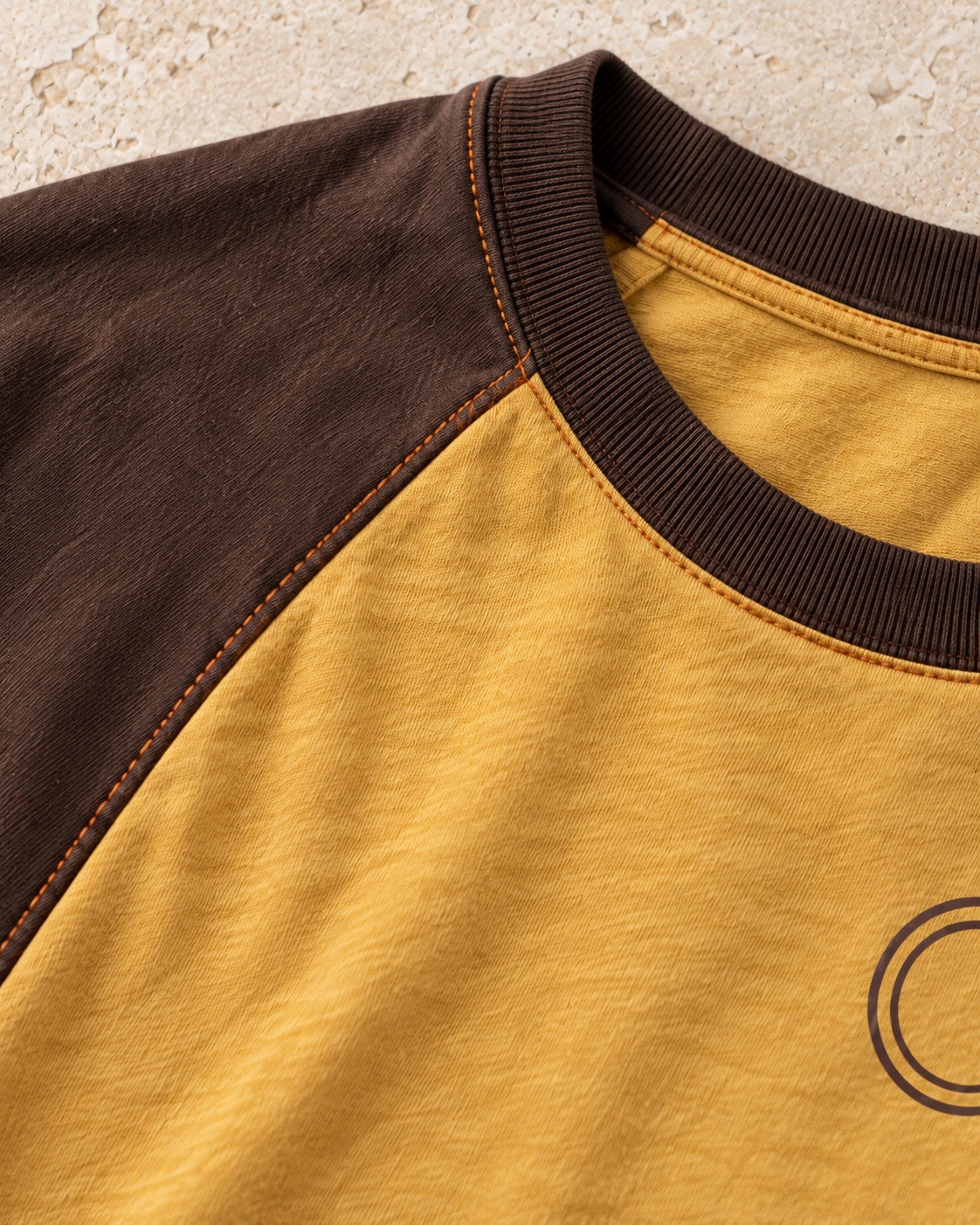 Fabric and construction close-up of the original contrast raglan t-shirt concept in mustard / espresso