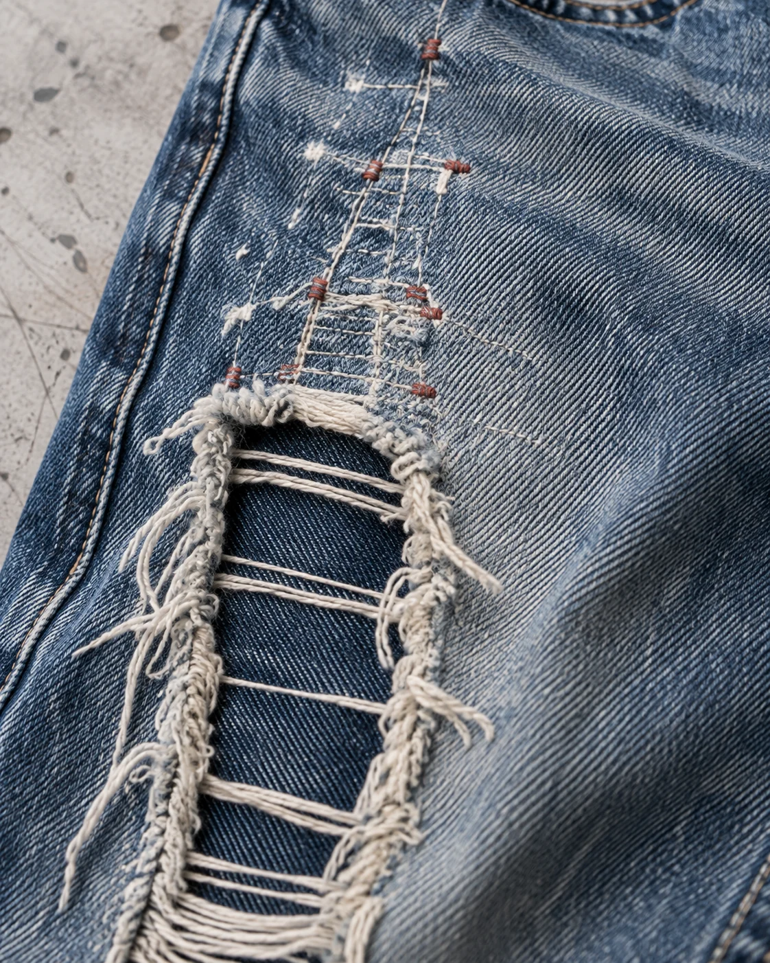 Close-up of fabric and signature construction — Distressed & Repaired Baggy Jeans in faded indigo / deep blue, AI-generated design concept