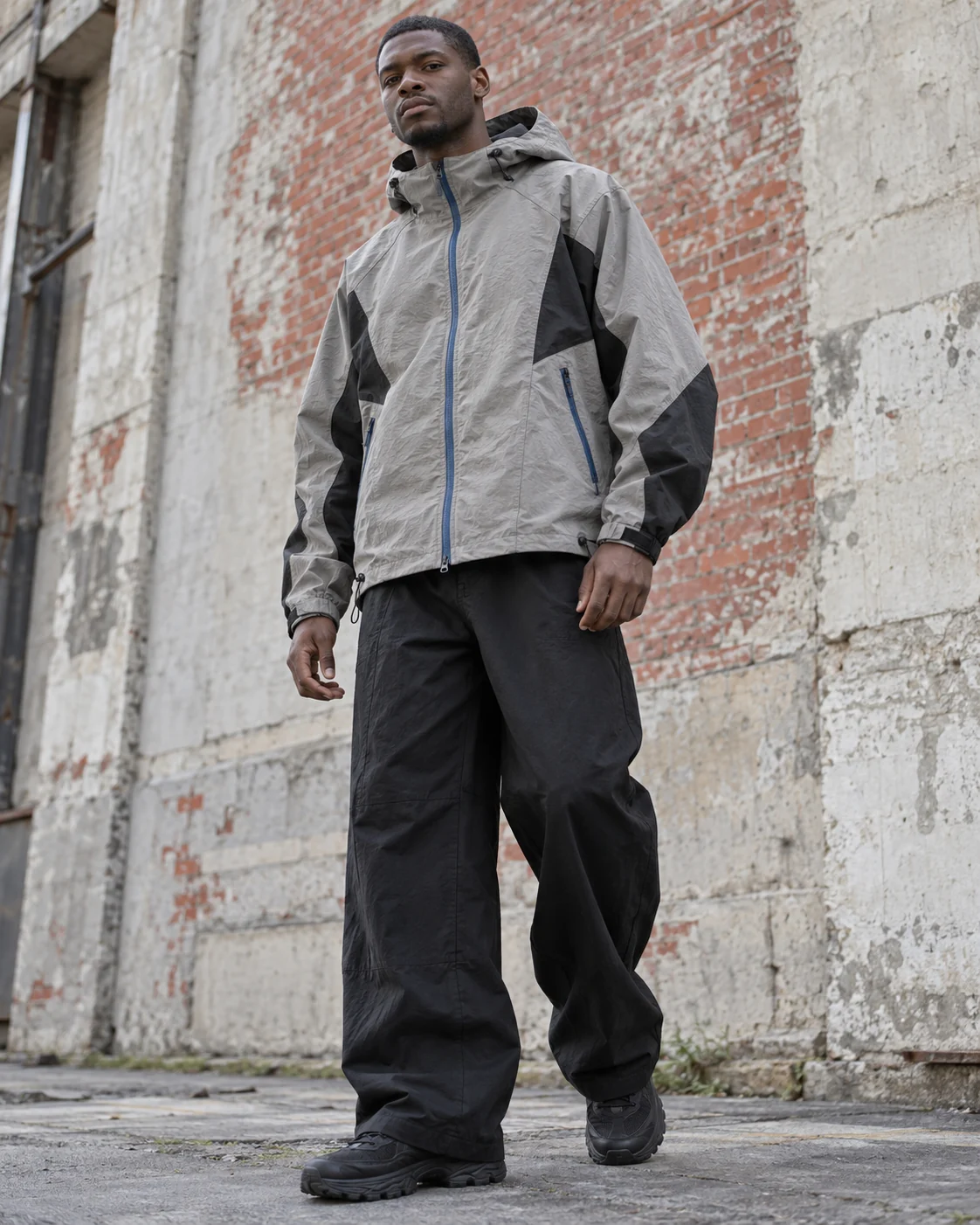 Front on-model view — Hooded Shell Jacket in stone grey / charcoal / cobalt, AI-generated design concept