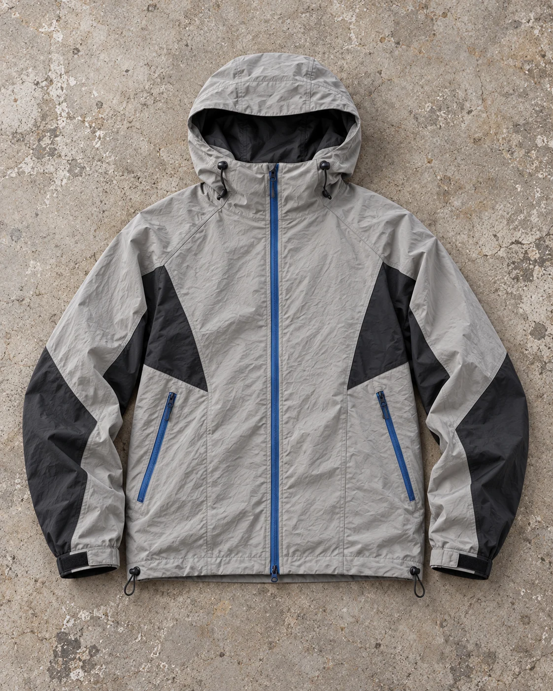 Full garment flat-lay showing the cut — Hooded Shell Jacket in stone grey / charcoal / cobalt, AI-generated design concept