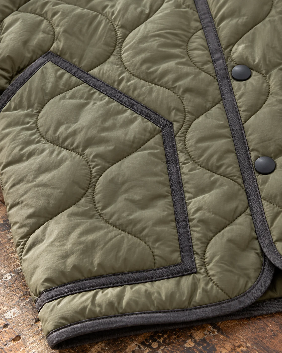 Close-up of fabric and signature construction — Quilted Liner Jacket in dusty moss / charcoal, AI-generated design concept