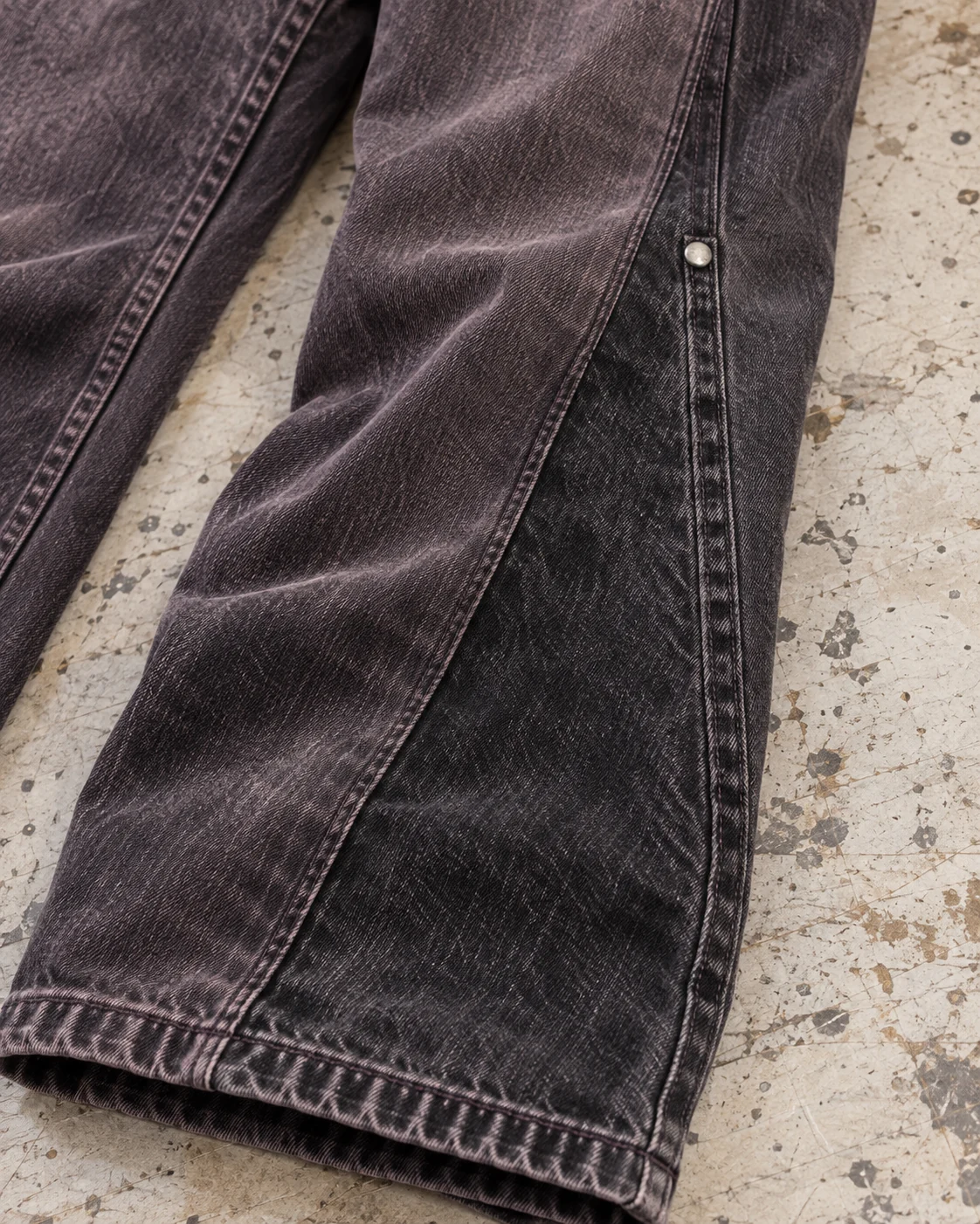 Close-up of fabric and signature construction — Relaxed Flared Jeans in faded plum black / charcoal, AI-generated design concept